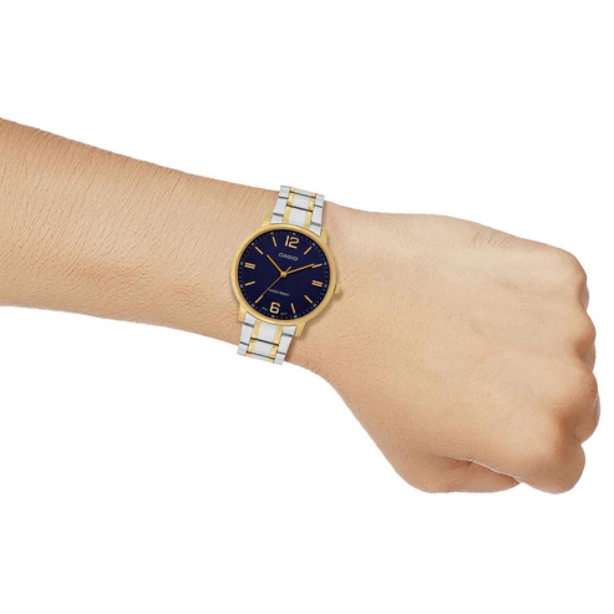 Wrist wearing a two-tone watch with a blue face on a white background