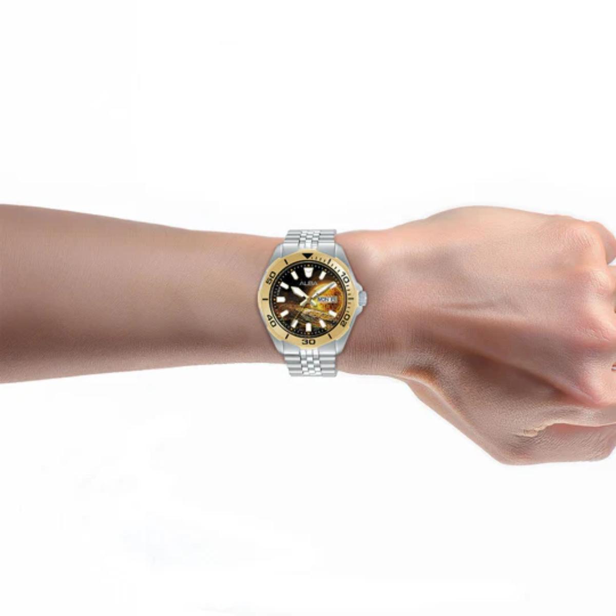 Wrist wearing a silver watch with a yellow and blue face on a white background