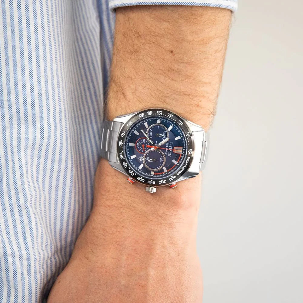 Wrist wearing a silver watch with a blue face on a light background