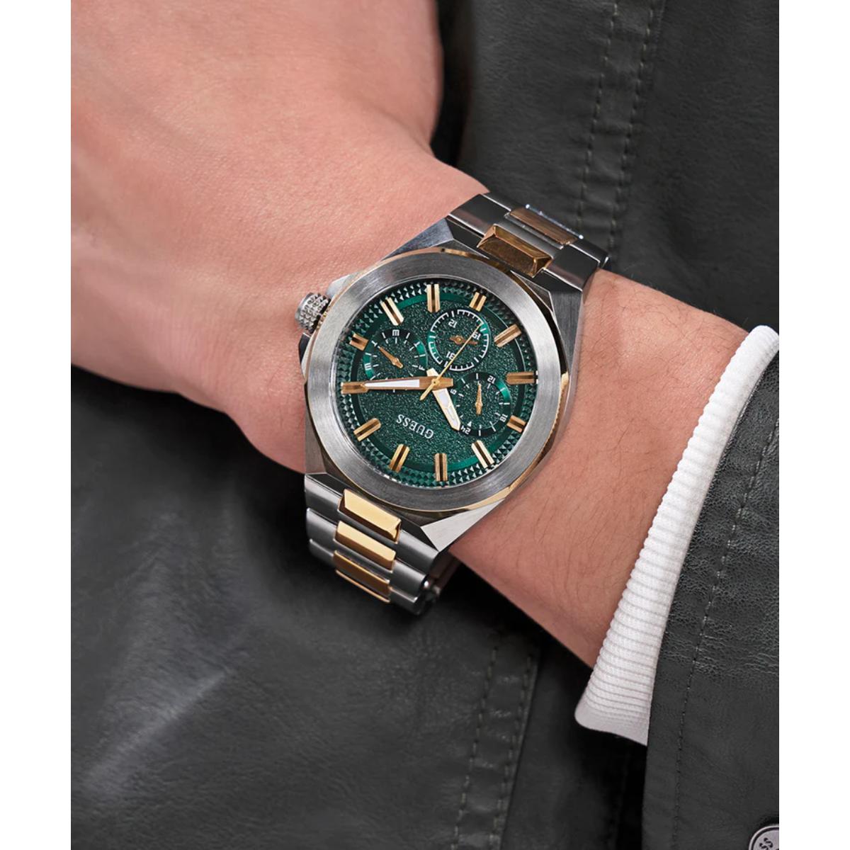 Silver and gold watch with green face on a person's wrist