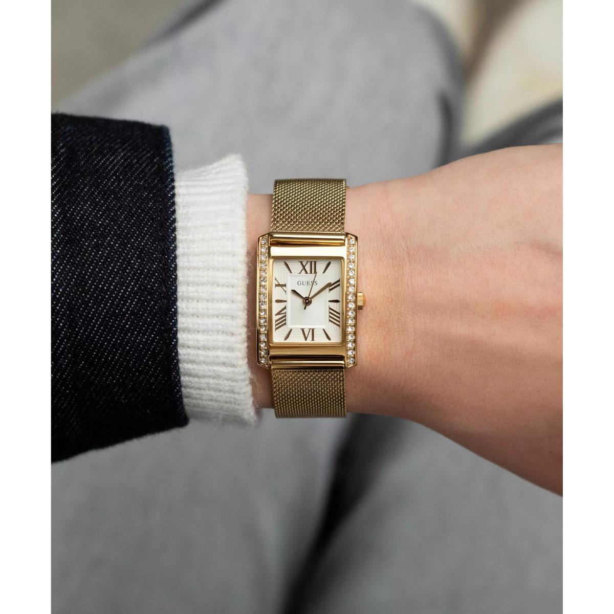 Gold watch on a wrist with a neutral background