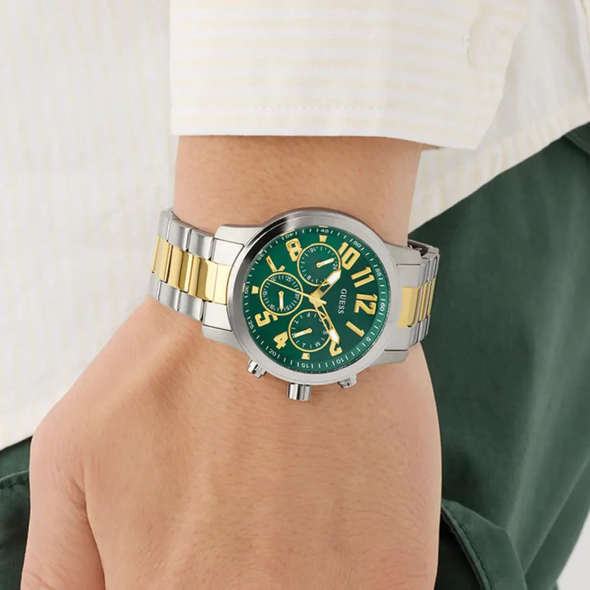 Green watch with gold accents on a wrist against a white background