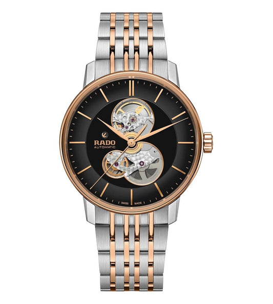 A Rado Coupole Classic Open Heart Automatic watch with a black dial, rose gold hands and markers, and a silver two-tone bracelet.