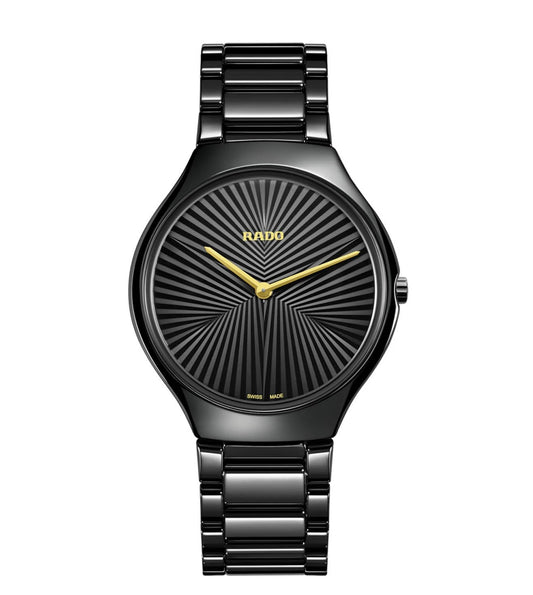 A black Rado True Thinline X Great Gardens of The World automatic unisex watch with a patterned dial and yellow gold colored hands.