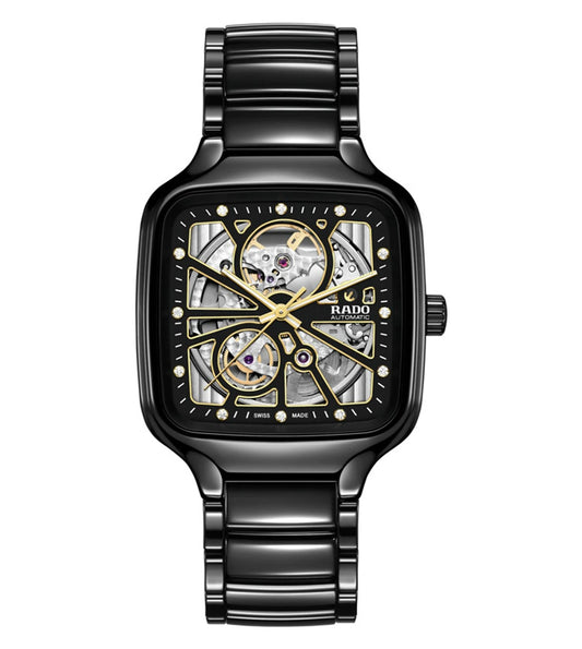 A black Rado True Square Automatic Open Heart watch with a silver open heart design on the dial, yellow gold-coloured hands, and a polished black high-tech ceramic bracelet.