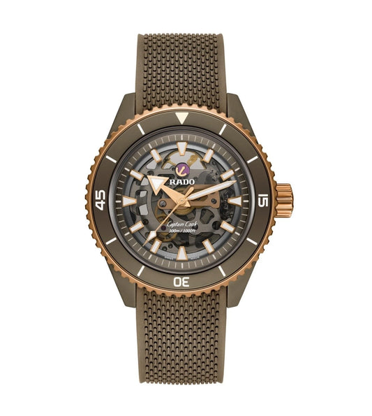 A Rado Captain Cook High-Tech Skeleton Automatic watch with a matte olive-green ceramic case and a rose-gold rotatable bezel, featuring a clear dial with geometric indices and hands.