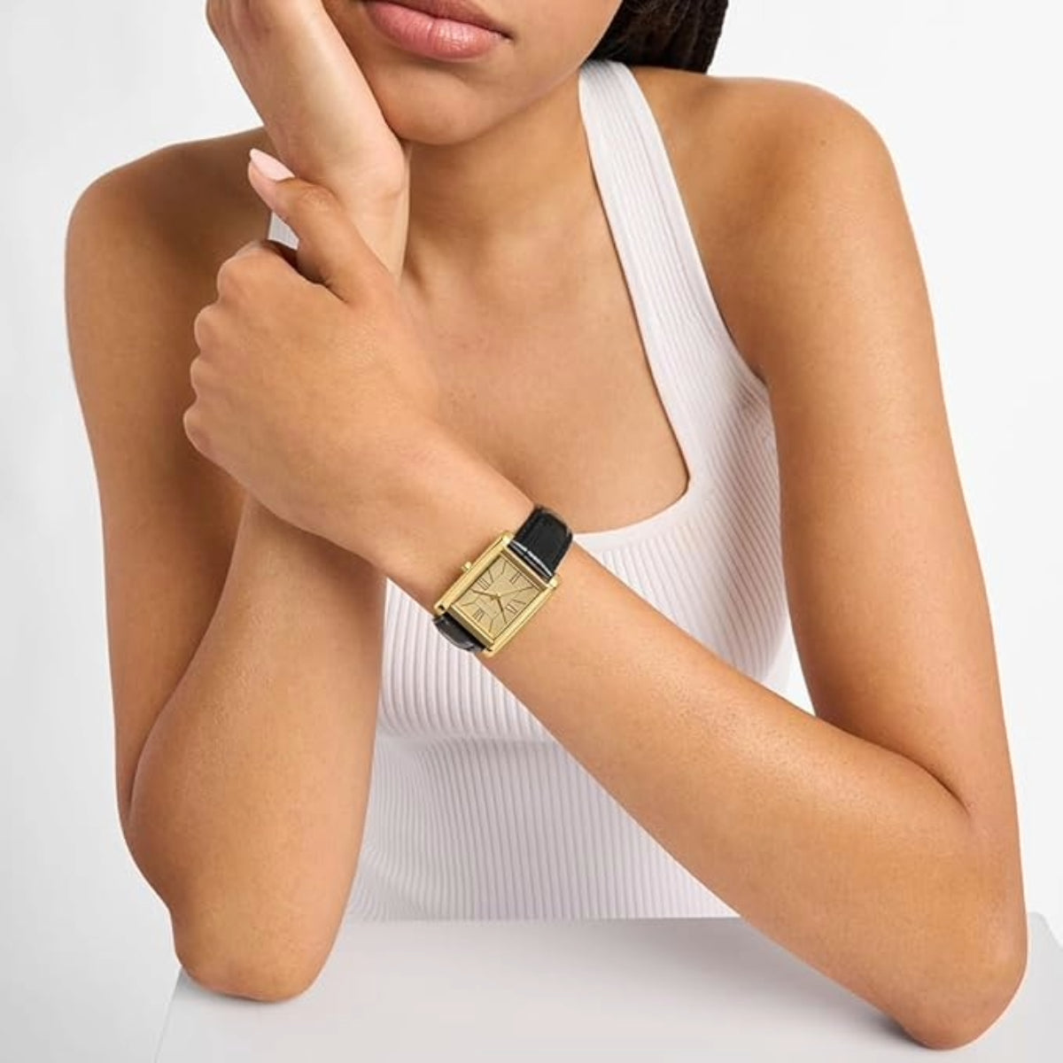 Woman wearing a gold watch on a plain background