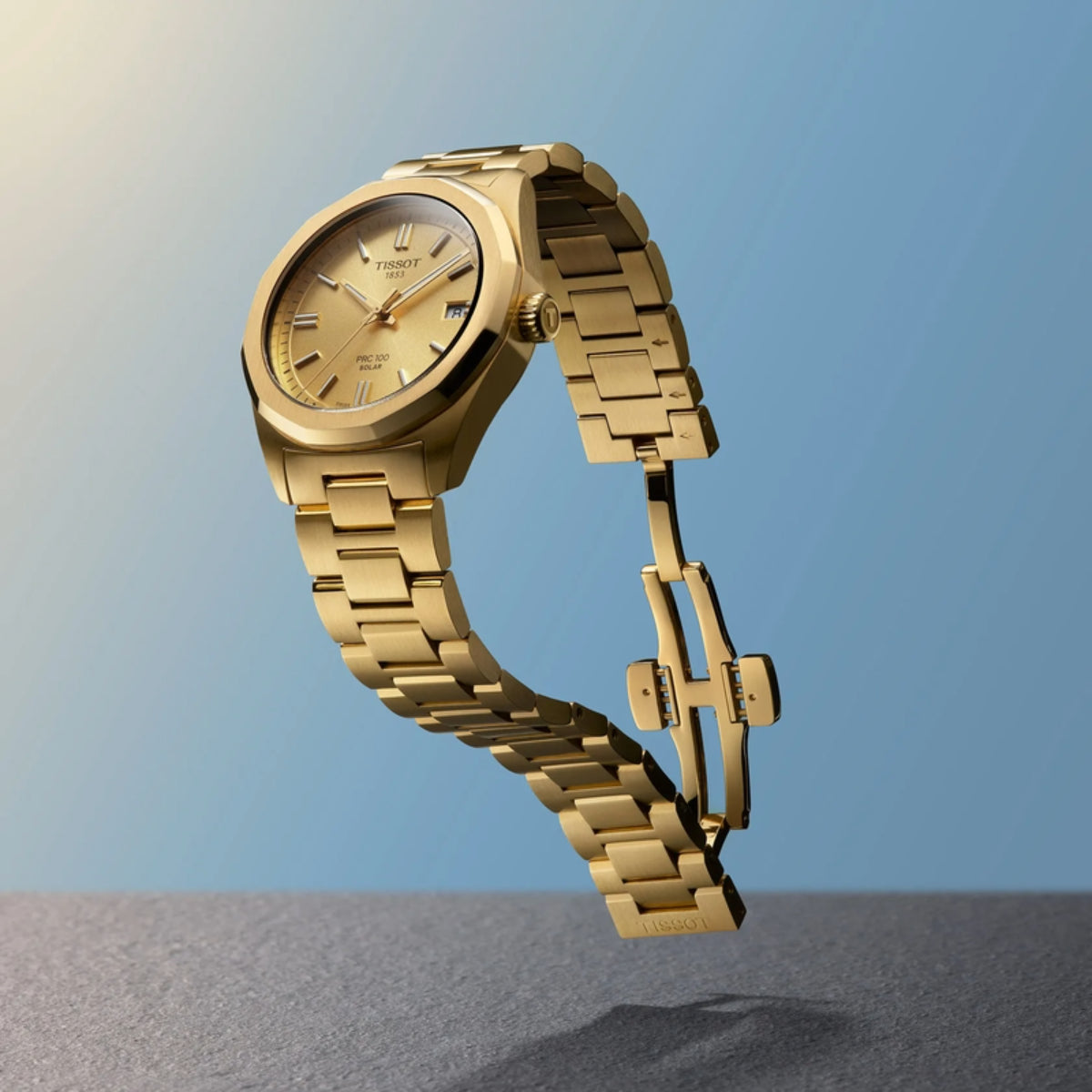 Gold watch with a Tissot logo on a blue gradient background