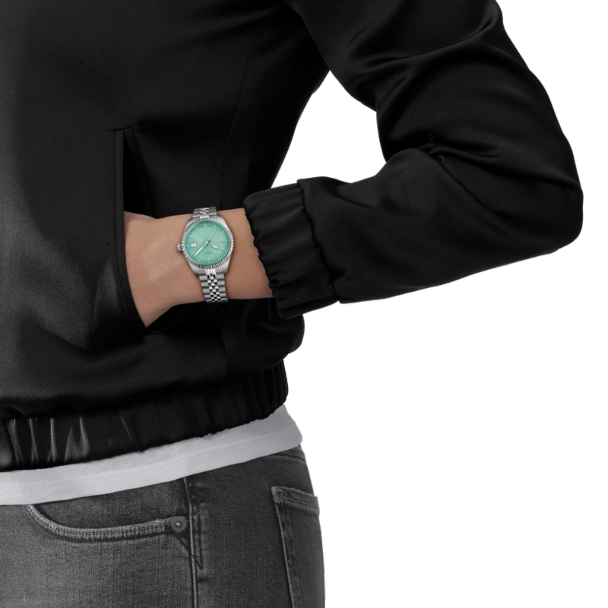 Person wearing a black jacket and gray jeans with a silver watch on a white background