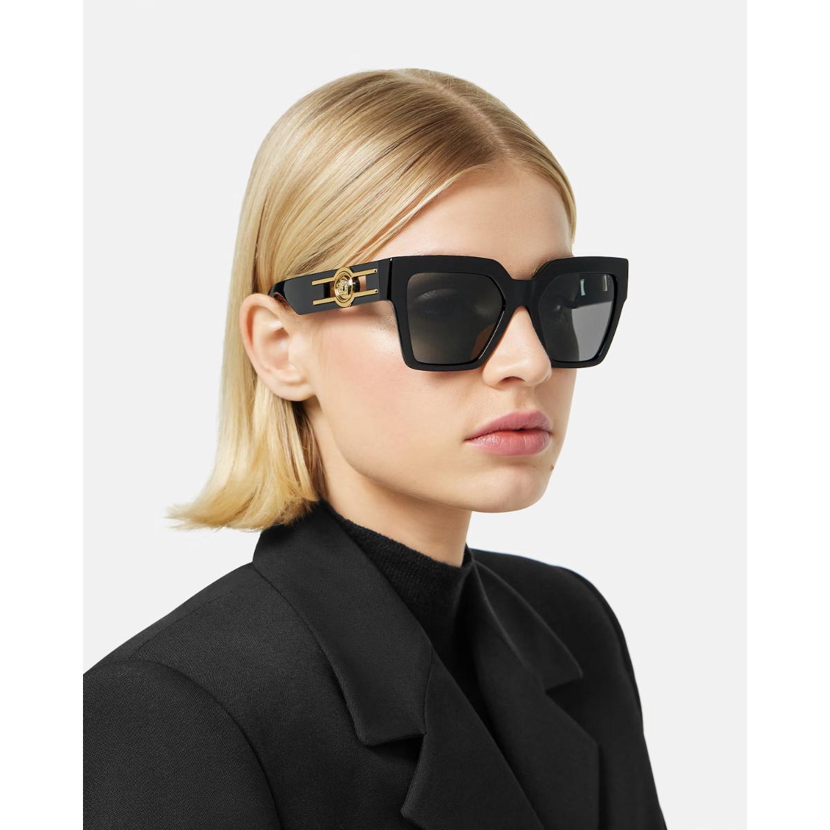 Person wearing black sunglasses with a gold frame on a white background