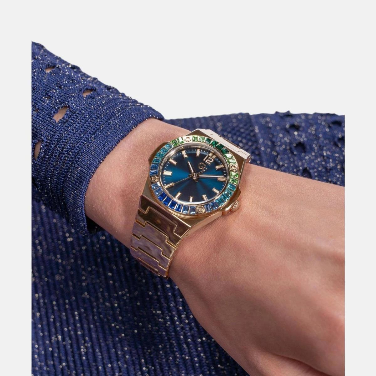 Luxury watch with blue face and rose gold case on a wrist against a blue textured background