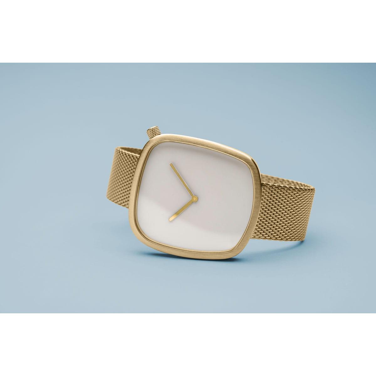 Gold watch with a white face on a light blue background