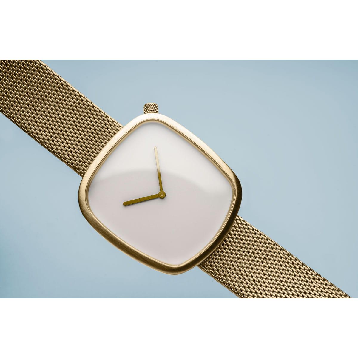 Gold watch with a white face on a light blue background
