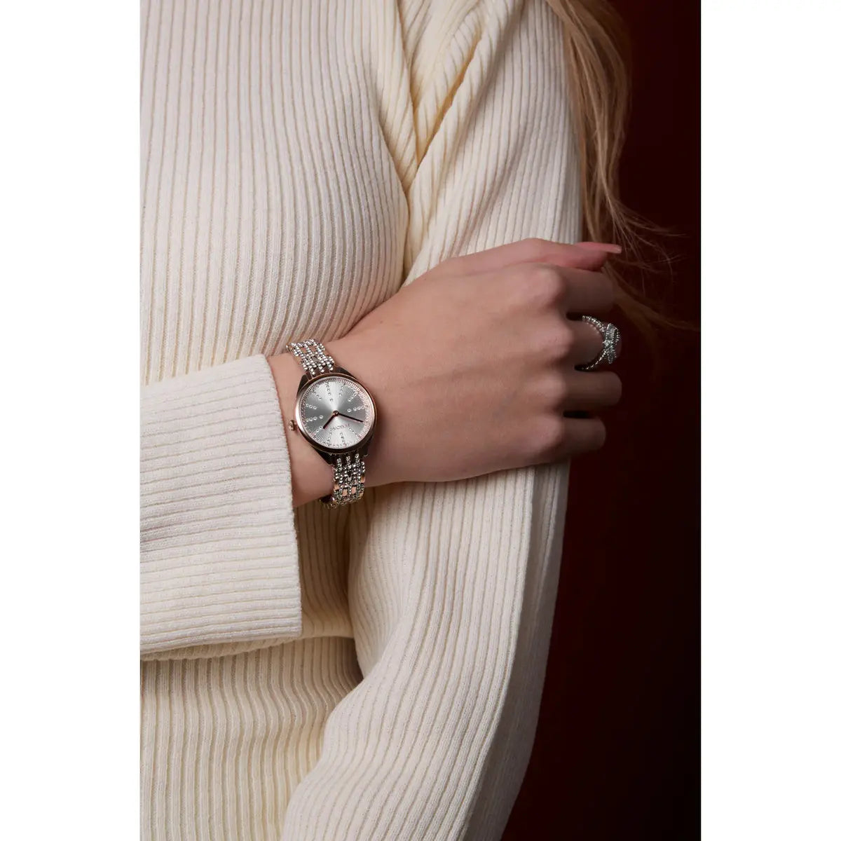 Person wearing a silver watch and ring on a white background