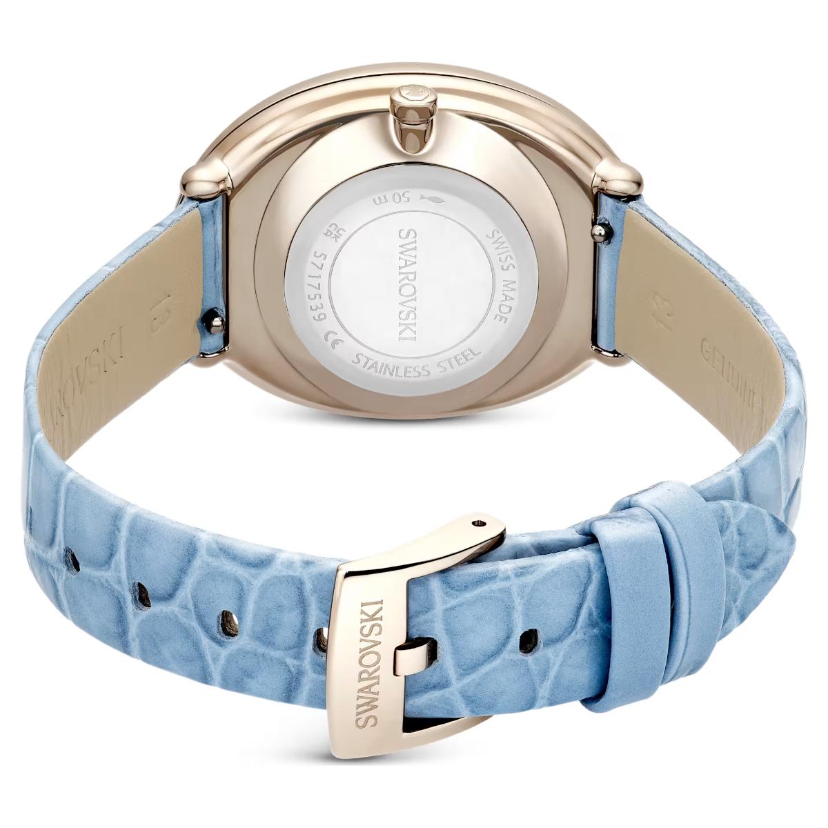 Swarovski watch with blue strap and rose gold case on a white background