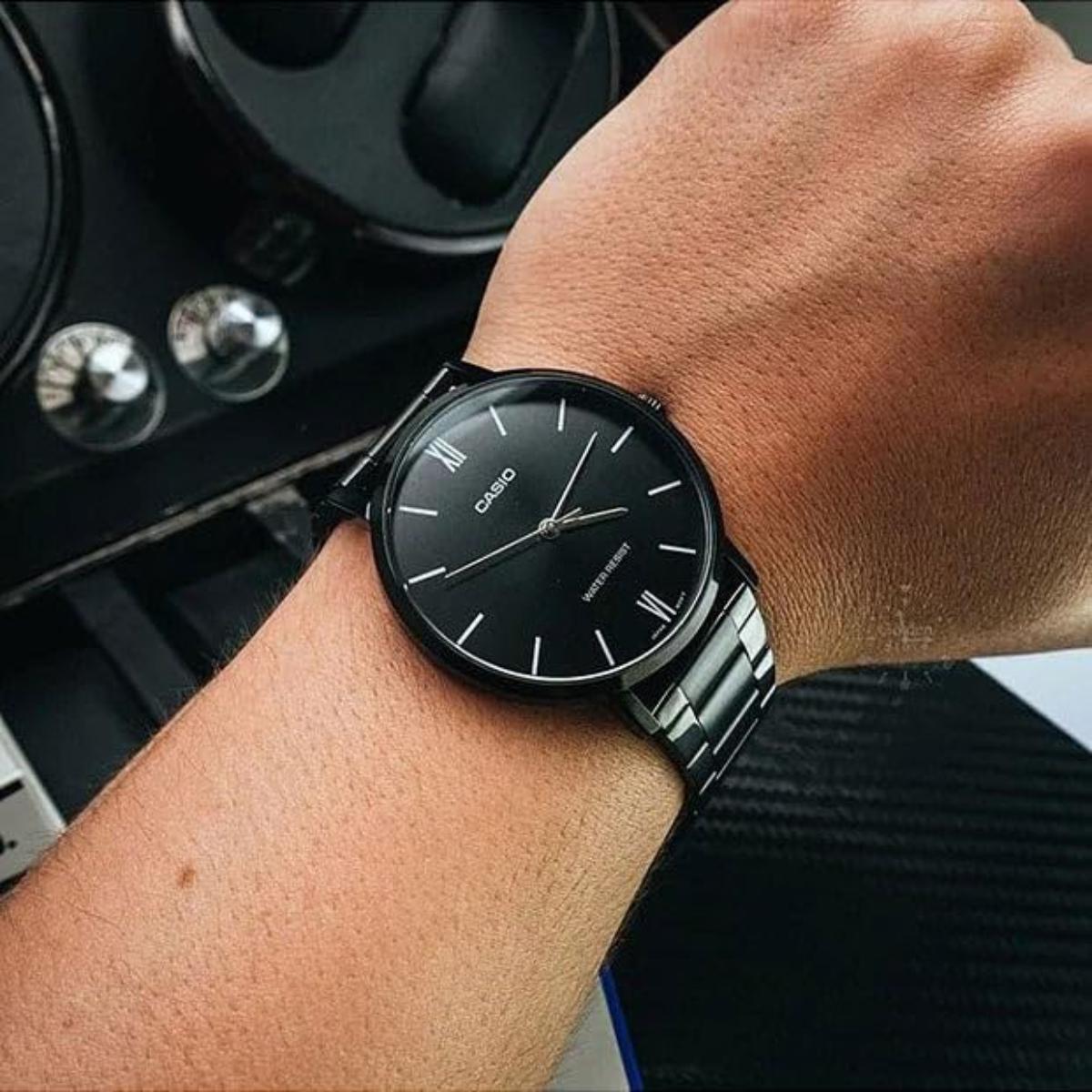 Person wearing a black watch with a car interior in the background