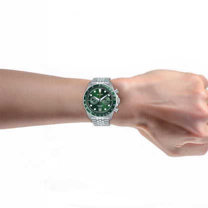 Hand wearing a silver watch with a green face on a white background