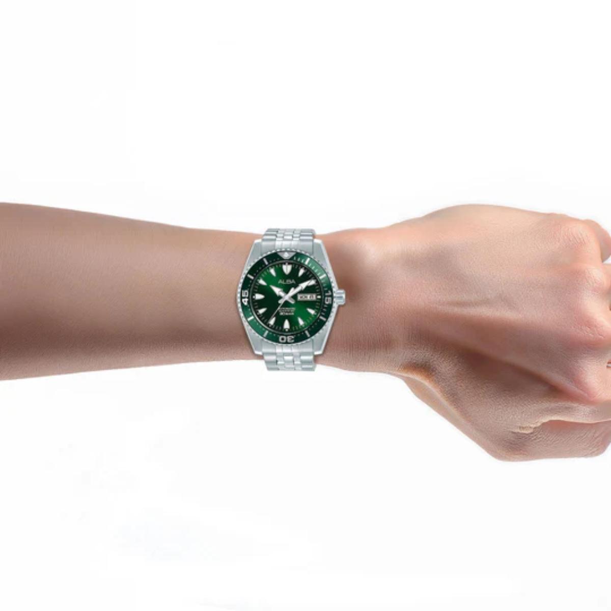 Wrist wearing a green watch with a silver case on a white background