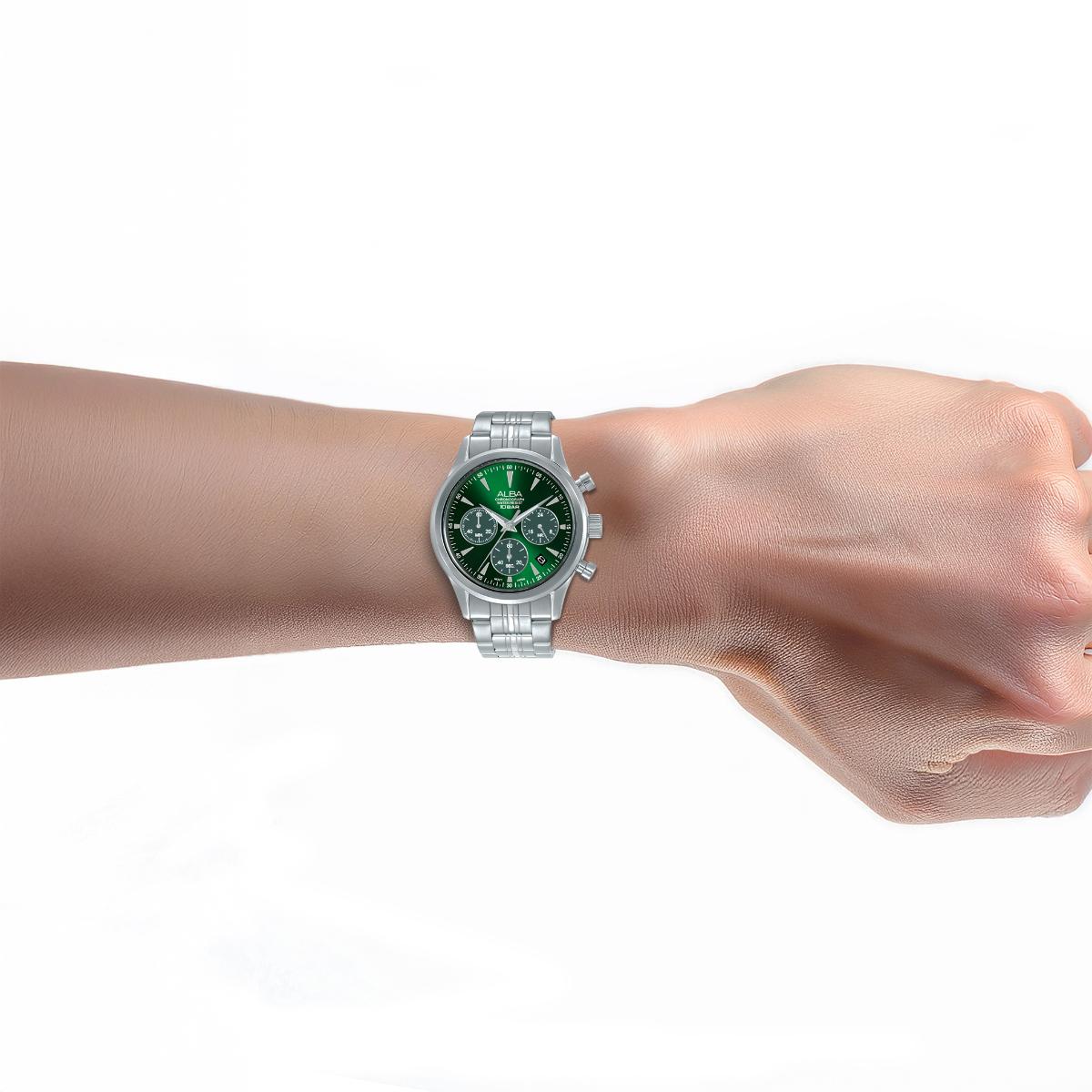 Silver watch with a green face on a wrist against a white background