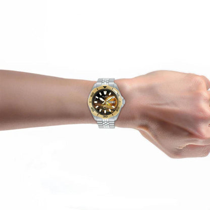Wrist wearing a silver watch with a yellow and blue face on a white background
