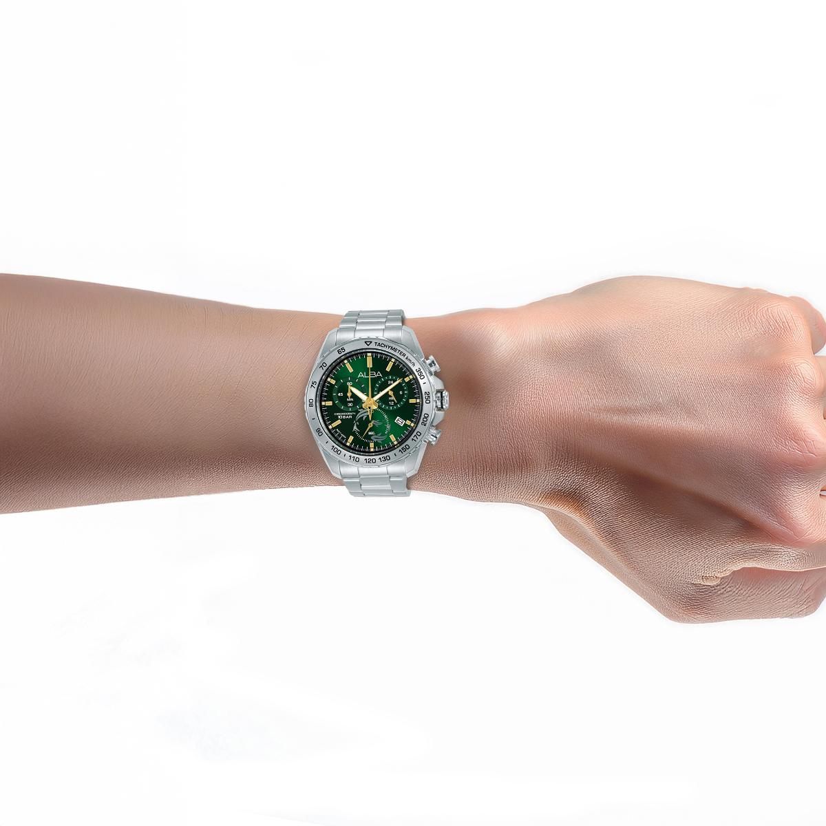 Hand wearing a silver watch with a green face on a white background