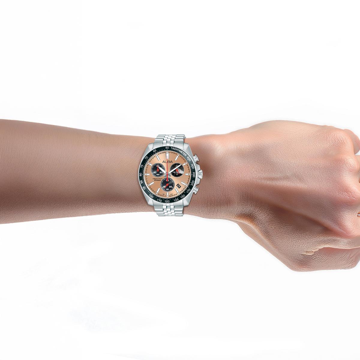 Wrist wearing a silver watch with a black and orange face on a white background