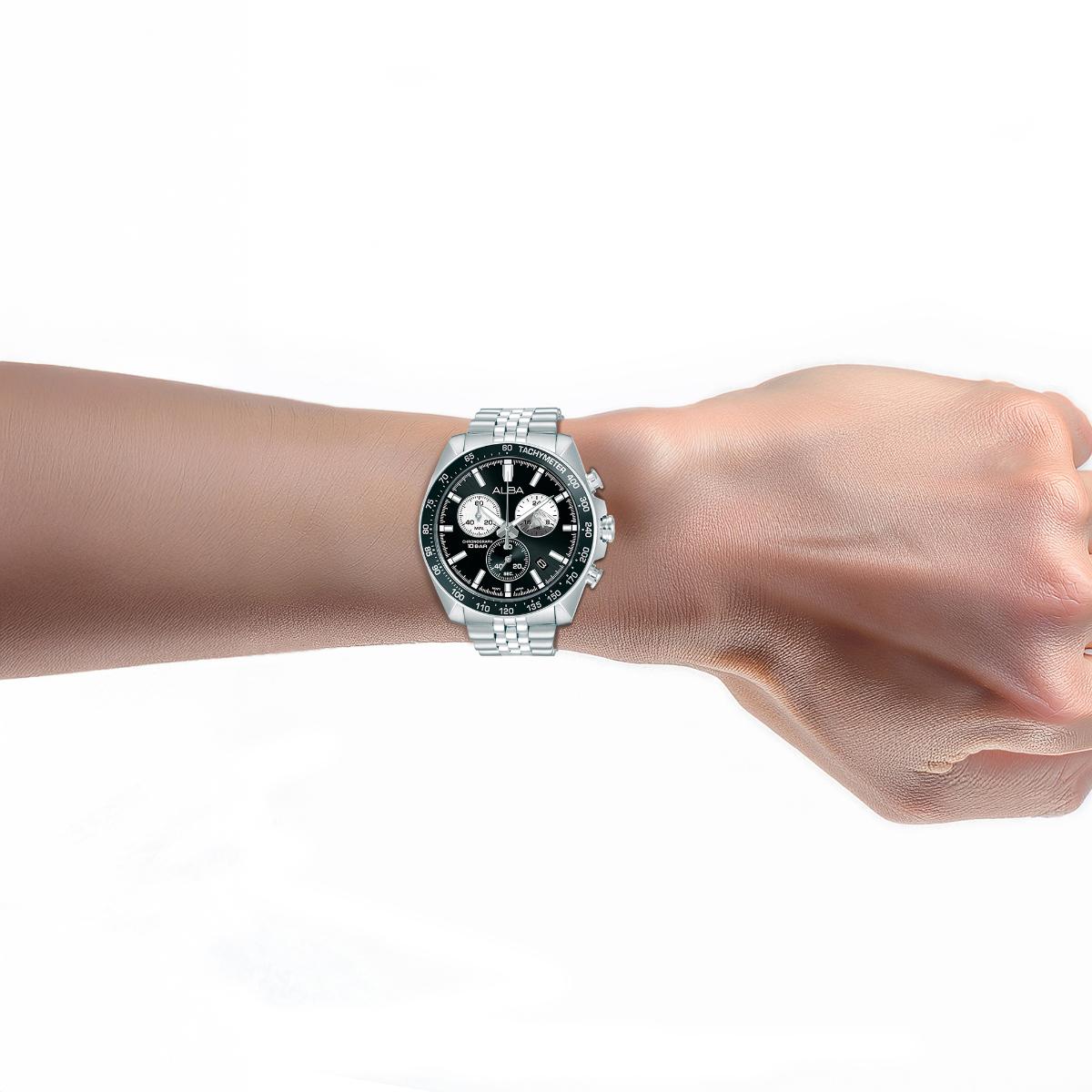 Wrist wearing a watch with a green face on a white background