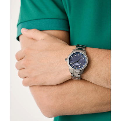 Person wearing a silver watch with a blue face on a white background