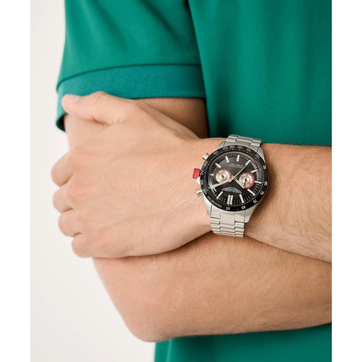 Person wearing a silver watch with a detailed face on a white background