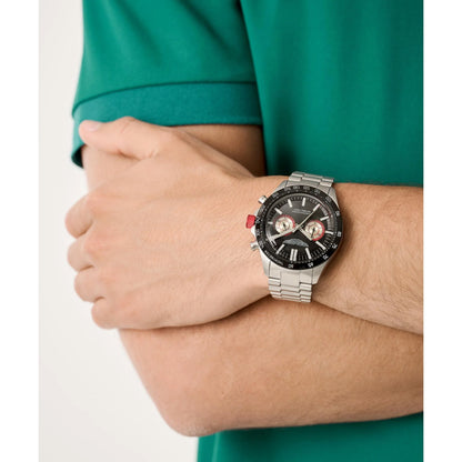 Person wearing a silver watch with a detailed face on a white background