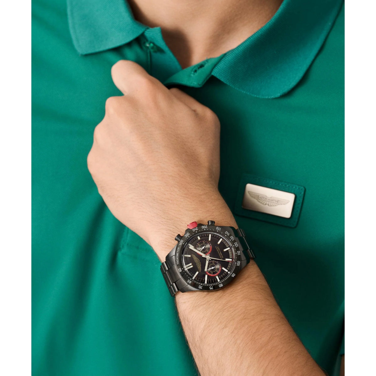 Person wearing a green polo shirt with a watch on their wrist