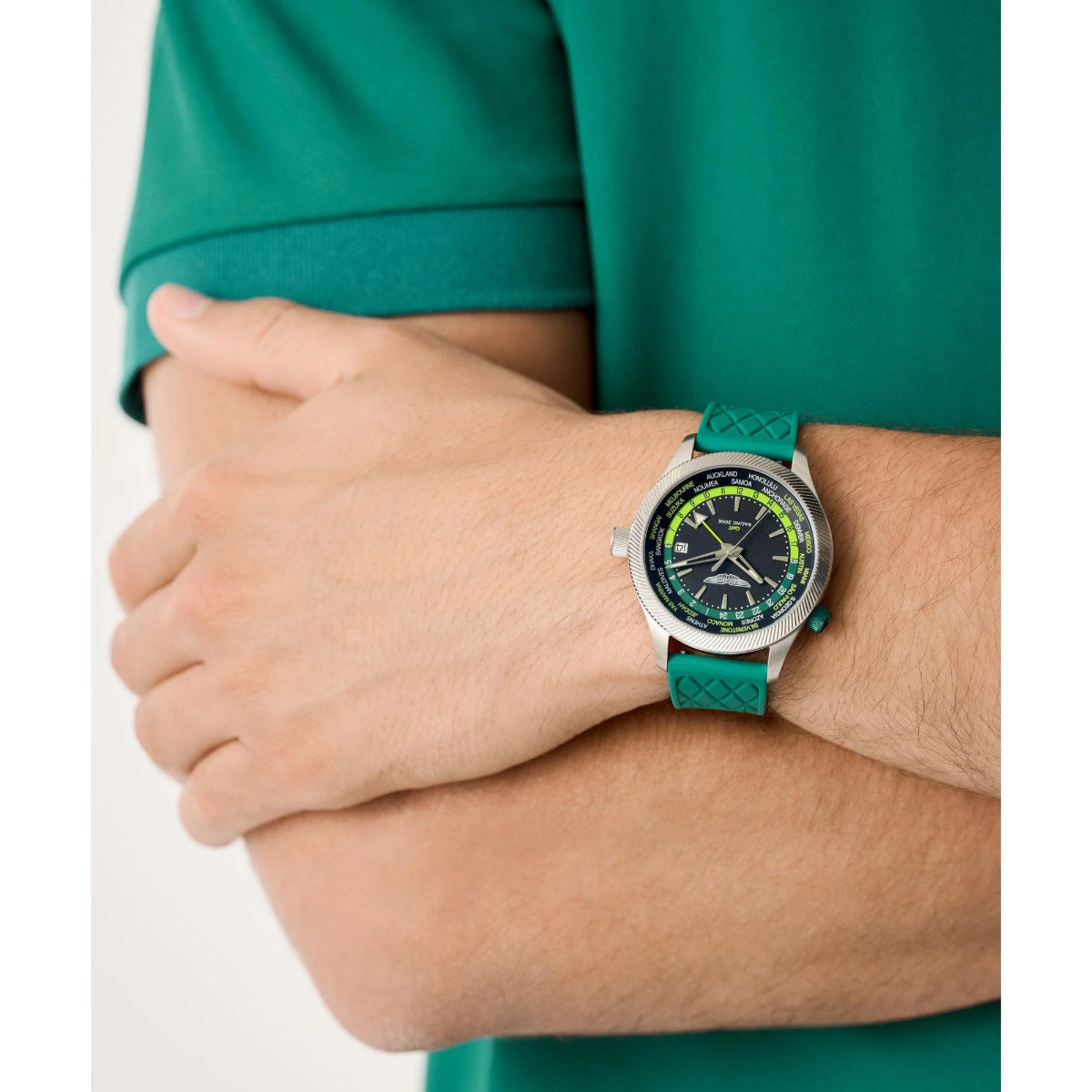 Person wearing a green watch with a matching shirt on a white background