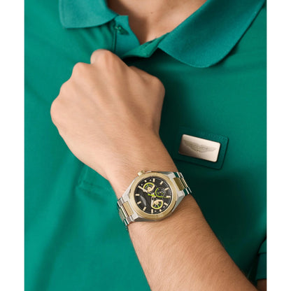 Person wearing a gold watch on a green shirt background