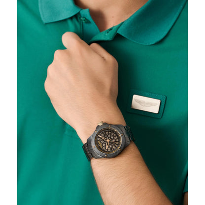 Person wearing a green polo shirt with a logo and a black watch on a white background