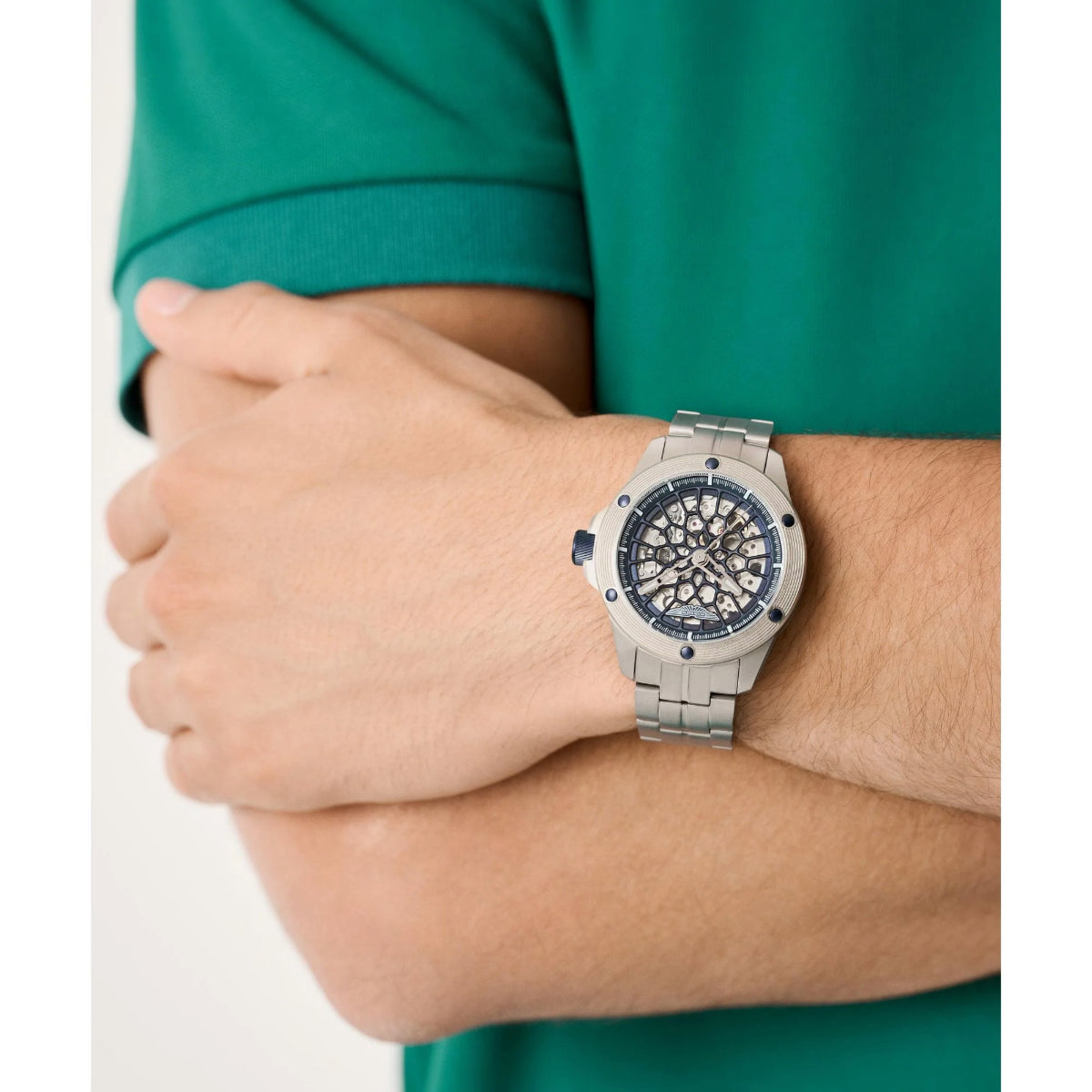 Person wearing a silver watch with a detailed face on a white background