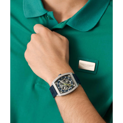 Person wearing a green shirt with a brand logo and a watch on their wrist.