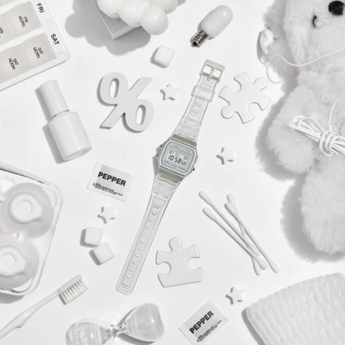 White digital watch surrounded by various items on a white background