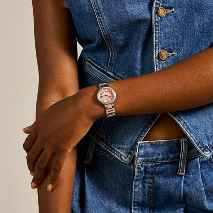 Person wearing a watch with a denim outfit on a neutral background