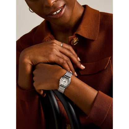 Person wearing a silver watch on a neutral background