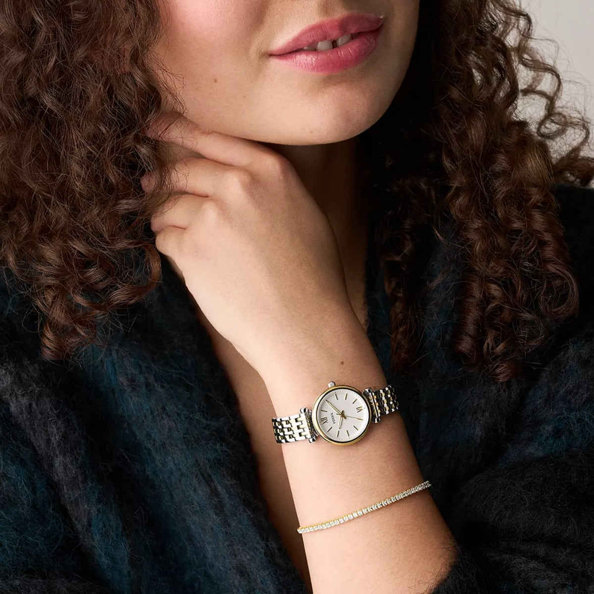 Woman wearing a watch and bracelet with a dark background