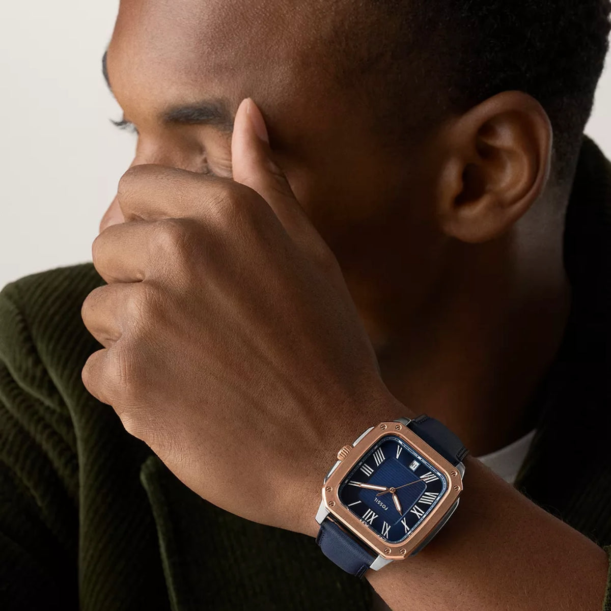 Person wearing a rose gold and blue watch with a neutral background