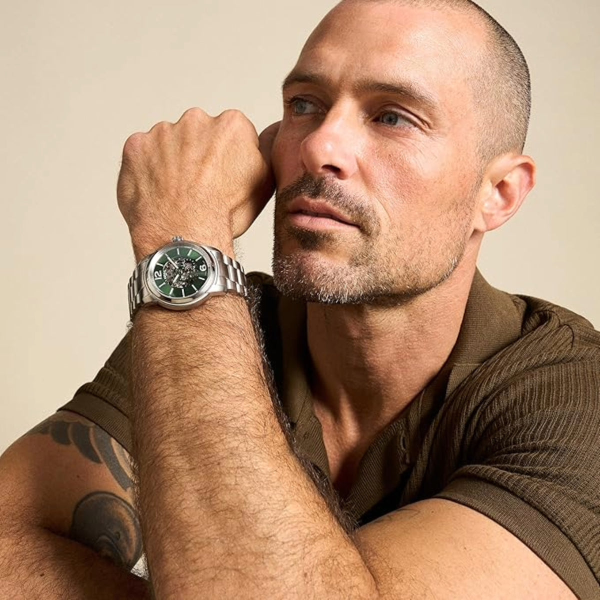 Man wearing a watch with a neutral background