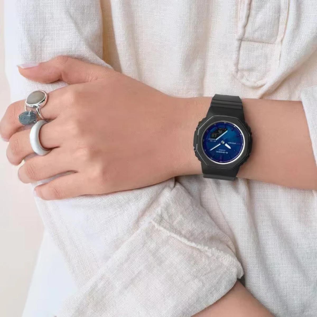 Person wearing a black smartwatch with a blue display on a light background