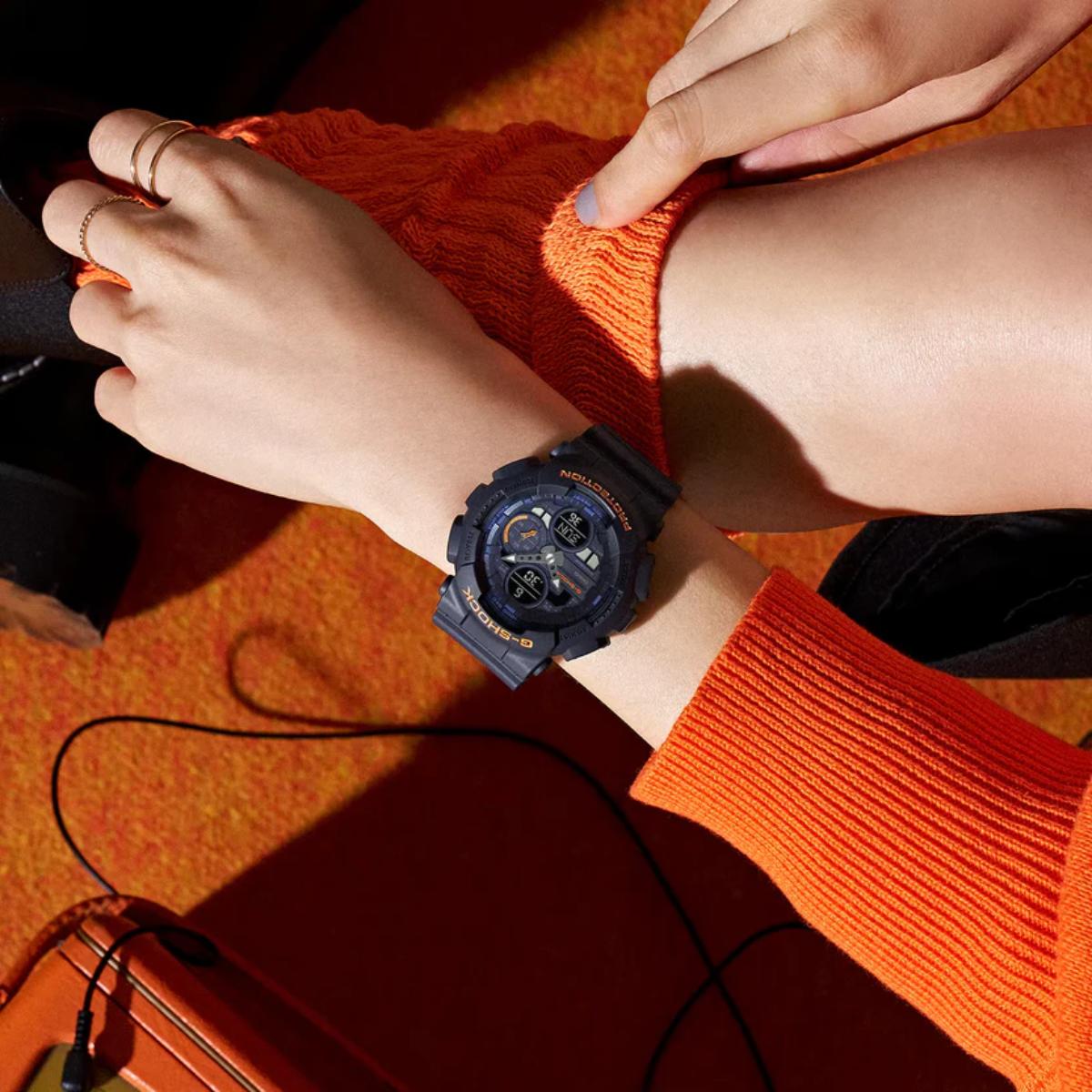 Person wearing a blue watch on an orange sweater with a blurred background