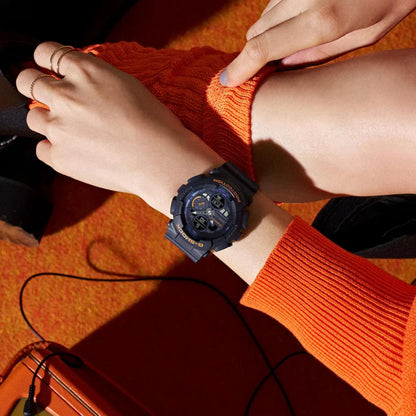 Person wearing a blue watch on an orange sweater with a blurred background