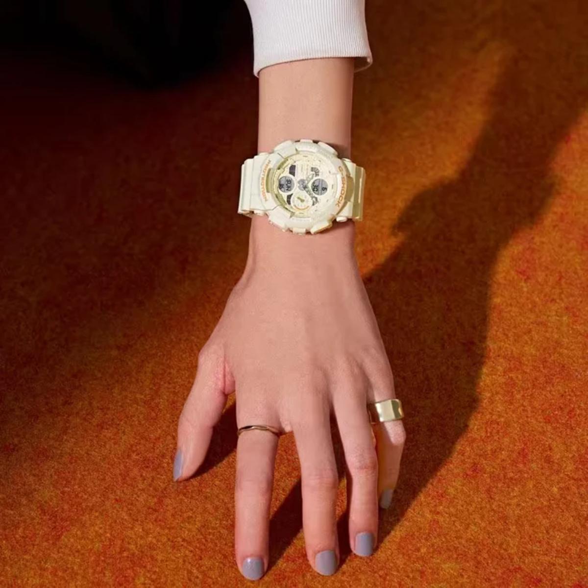 Gold watch on a wrist with a plain background