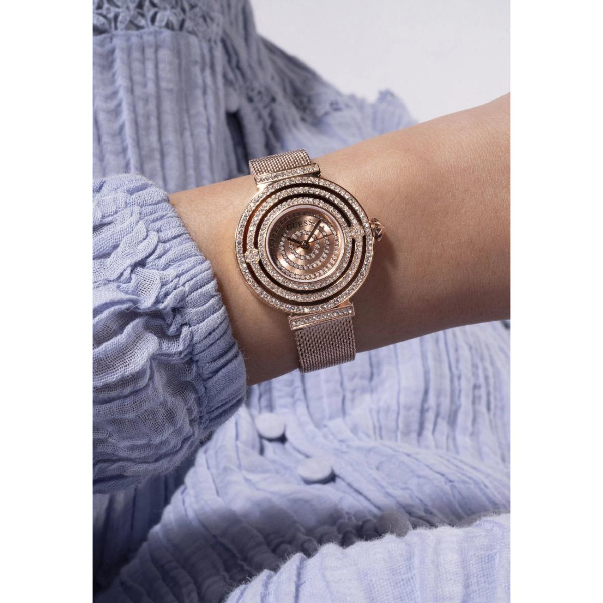 Rose gold watch on a wrist with a textured blue fabric background