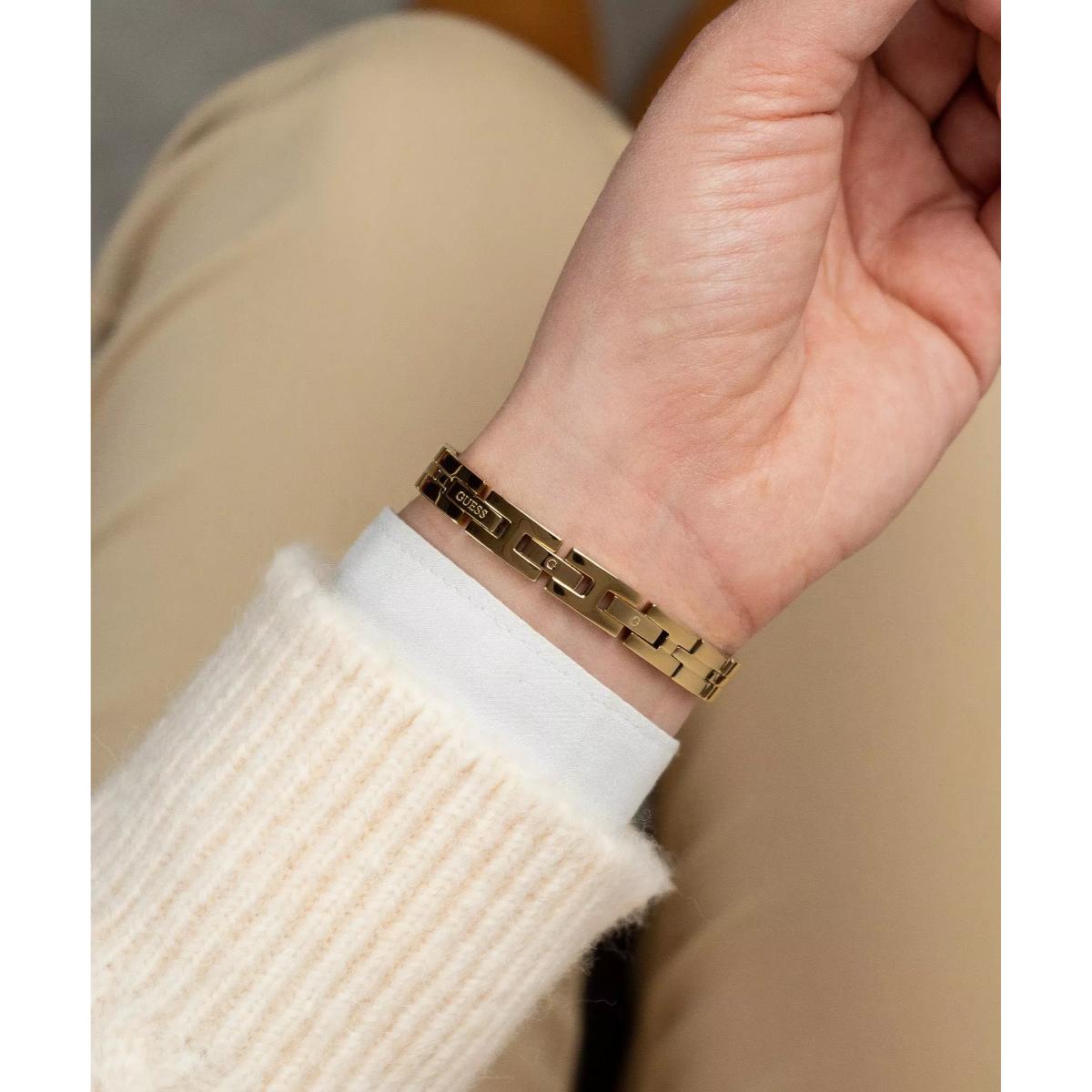 Gold bracelet on a wrist with a neutral background