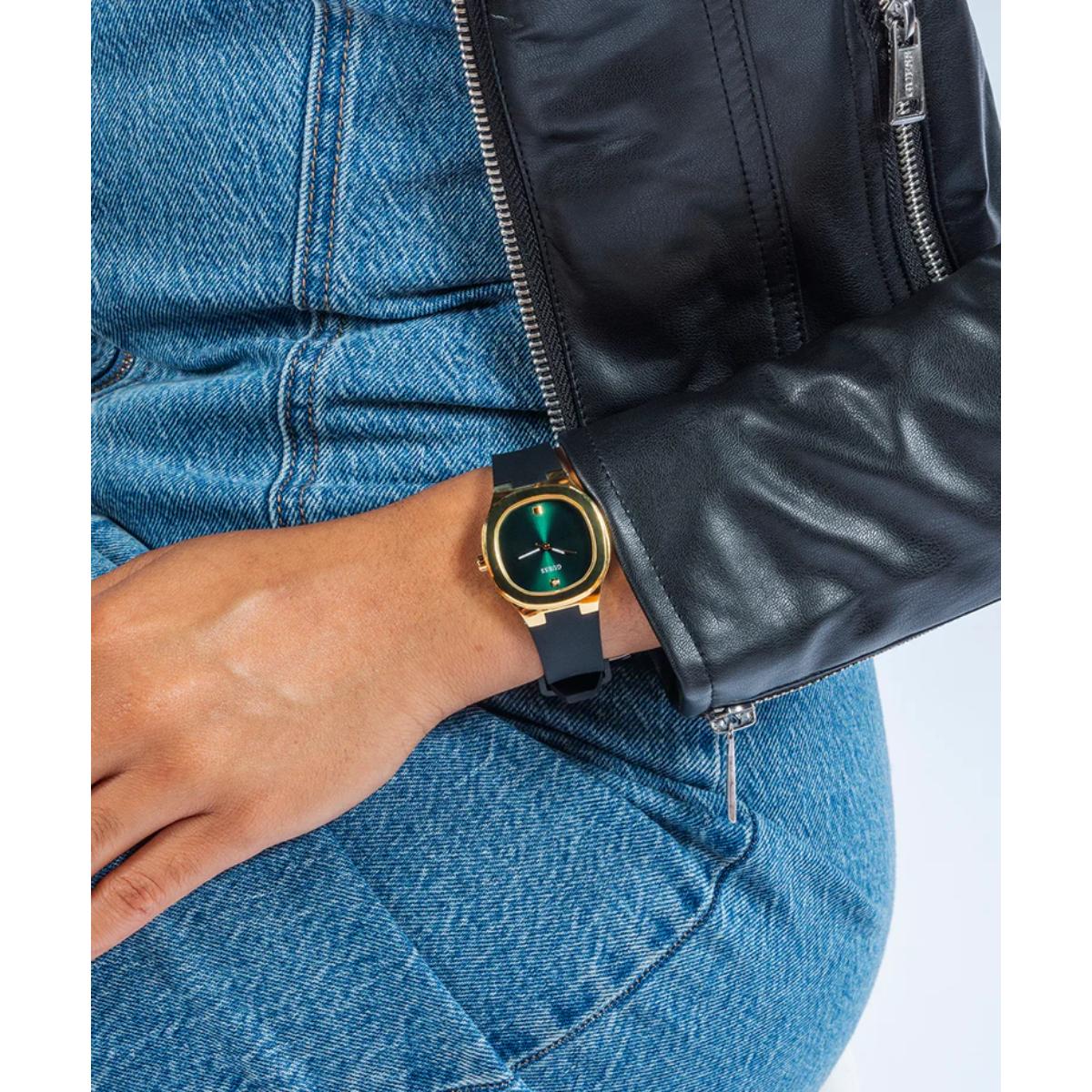 Person wearing a black leather jacket and blue jeans with a watch on their wrist.