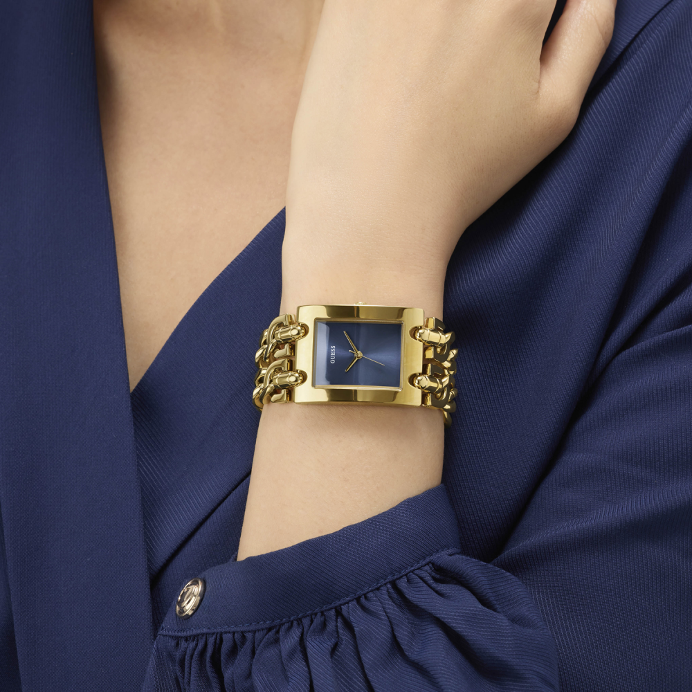 Gold watch with blue face on a wrist, wearing a navy outfit
